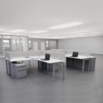 A spacious open office featuring multiple desks and chairs arranged for collaborative work.